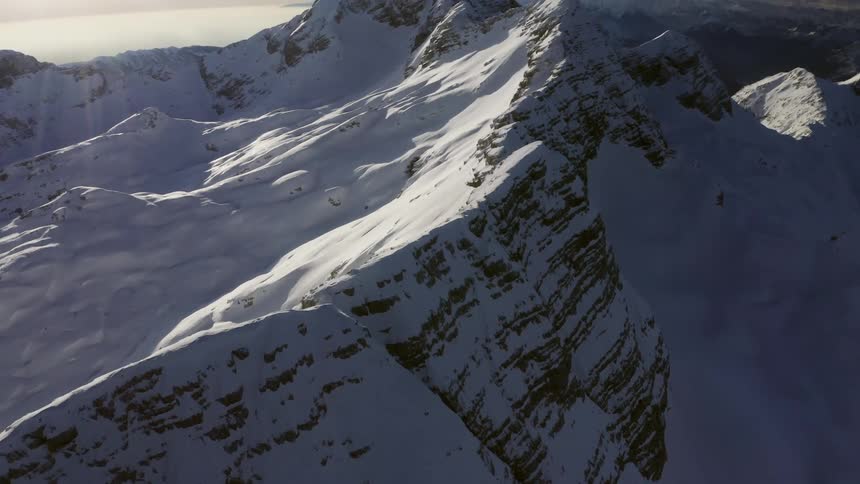 A mountain range covered with ice and snow with the sky and clouds in the background