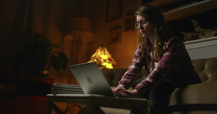 Woman sitting on a couch in her living room typing on a laptop