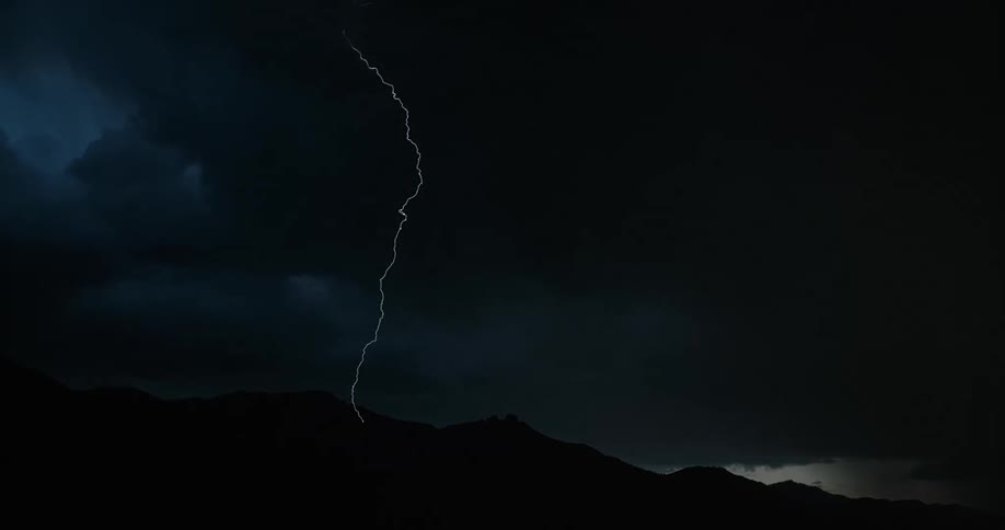 Lightning illuminating a dark cloudy sky during a rainstorm