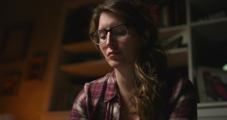 A woman in a room with glasses with shelves and a wall in the background