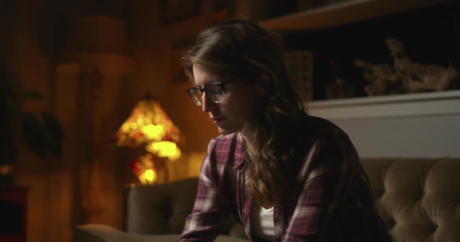 A woman sits at home and uses her laptop