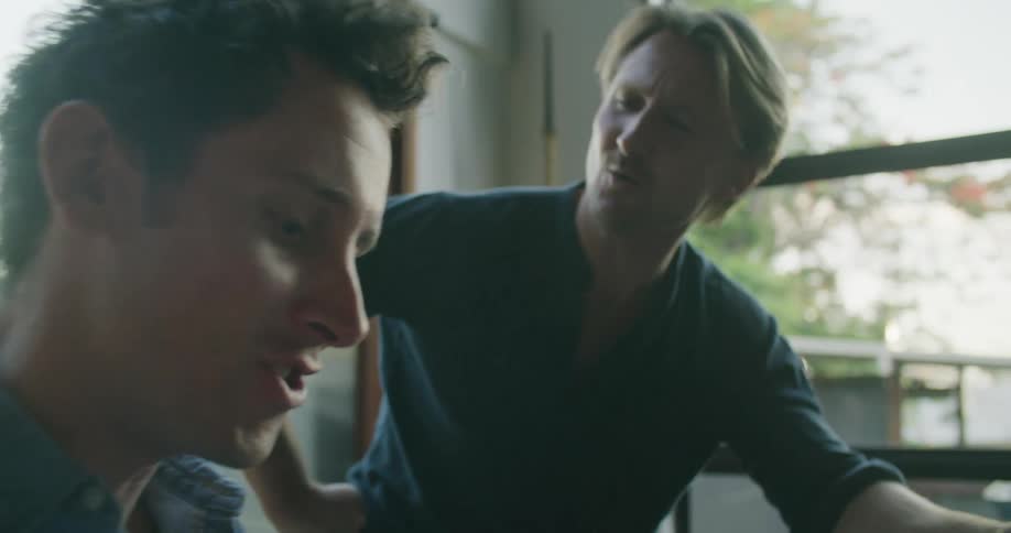 Two men playing piano and singing along in a room at home