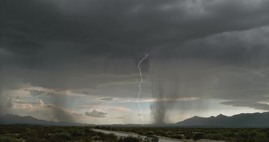 Bolts of lightning strike the ground beneath large and gray storm clouds