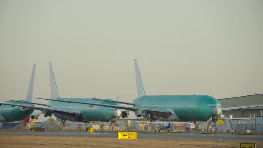 Visual contrast of a Cessna 170 taxiing next to massive Boeing 777 aircraft under assembly at Paine Filed in Everett, Washington State