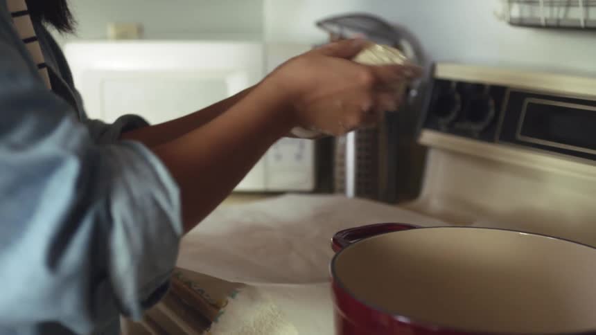 Young woman places a risen ball of dough inside a cooking pot in the kitchen