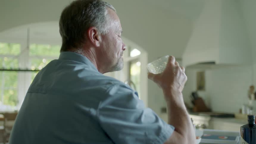 A man and woman drinking cocktails in a home kitchen