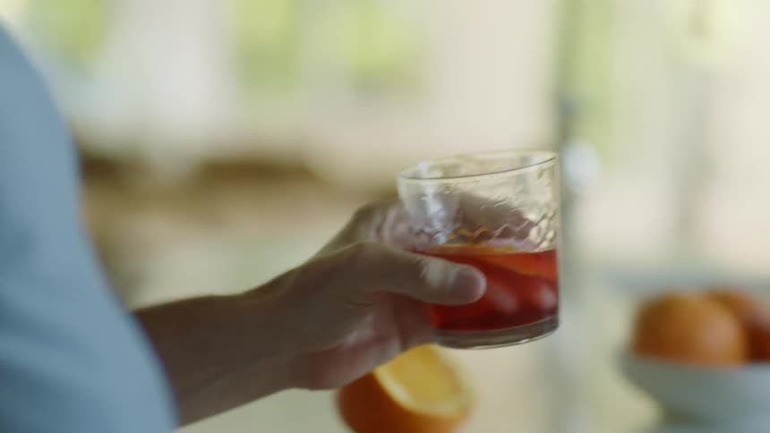 A man sitting at home takes a drink and sets it on a table