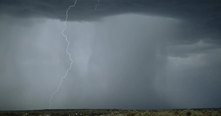 Lightning bolts flash from dark storm clouds and hit the ground