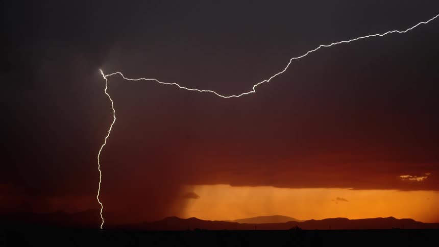 A storm with lightning over a landscape with the sky and clouds in the background