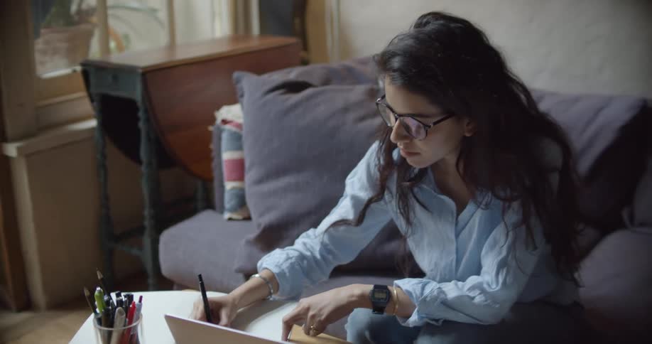 A woman sitting around writing next to a laptop