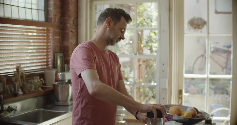 A man making a smoothie in a blender in a home kitchen
