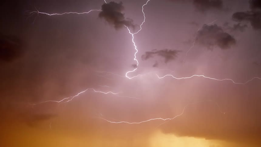 Lightning strikes scatter across an orange and yellow cloudy sky