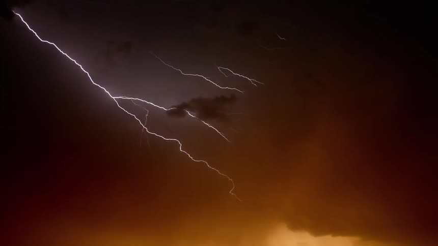 Countless bolts of lighting flash from the clouds hovering above a red sky during a massive storm