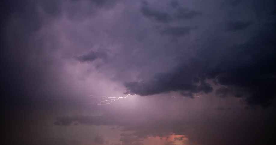 Lightning streaking arcs flashing across storm clouds over a field