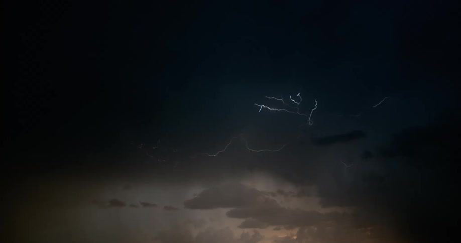 Lightning bolt flashes and branches out around storm cloud in dark sky