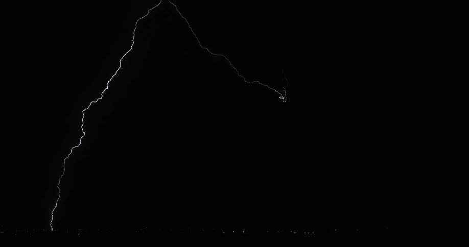 Lightning bolts flash and branch out in a dark sky