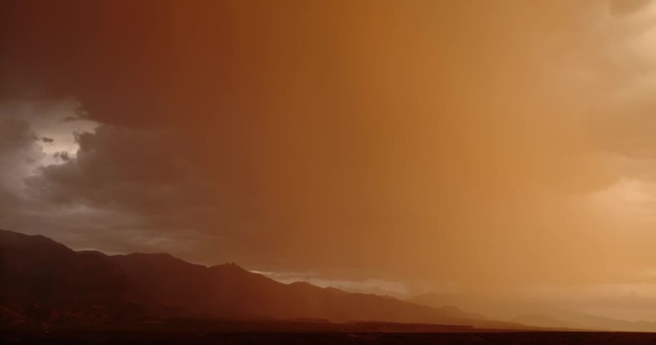 Lightning bolt comes down near mountains under an orange stormy sky