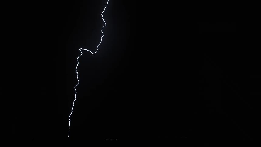 Lightning streaking arcs flashing across storm clouds hitting the ground over a field at night