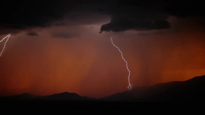Powerful bolts of lighting shot out of the clouds above a red sky and strike the mountains below
