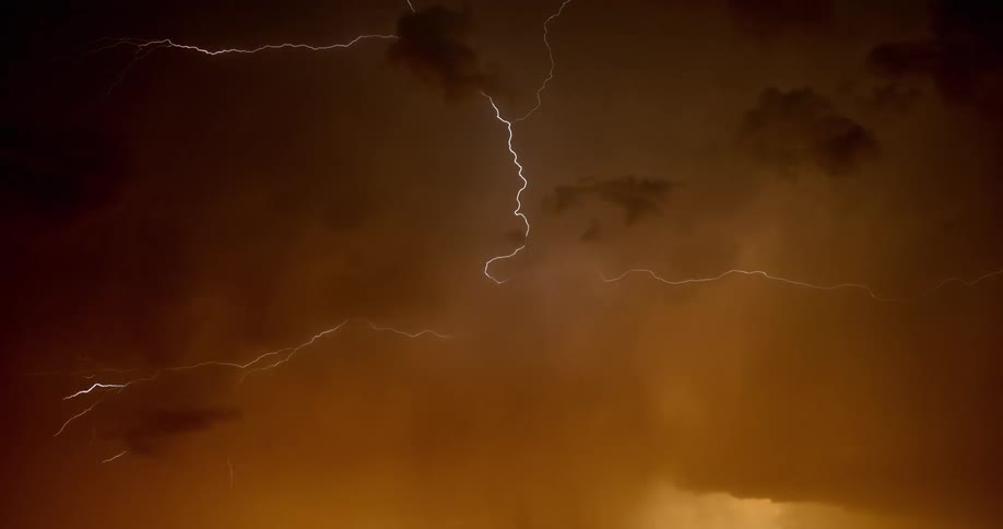 Lightning streaking arcs flashing accross yellow storm clouds