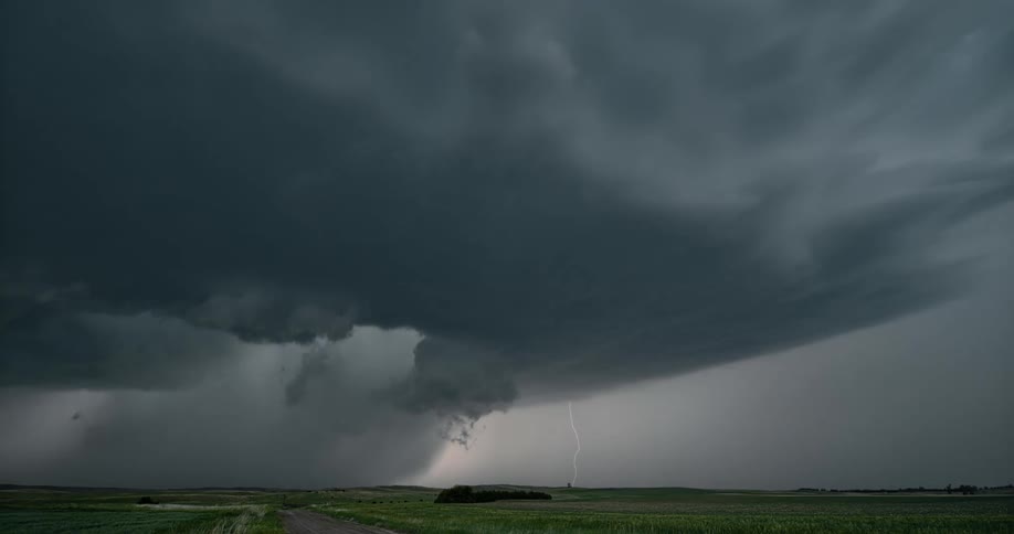 Bolts of lightning strike the ground beneath large and ominous gray storm clouds