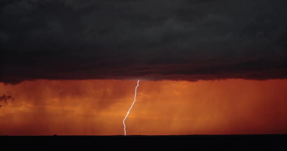 Several powerful bolts of lightning strike the ground beneath massive and dark storm clouds