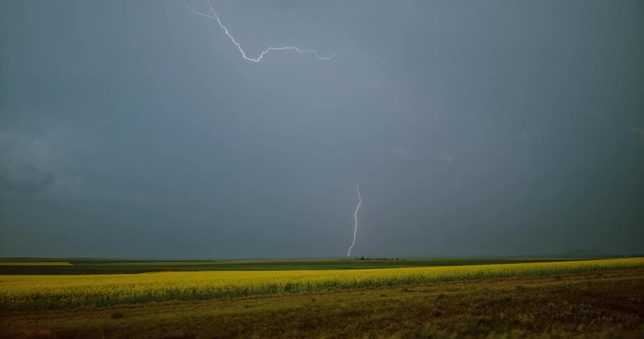 Lightning bolts flash and hit the ground near farmland