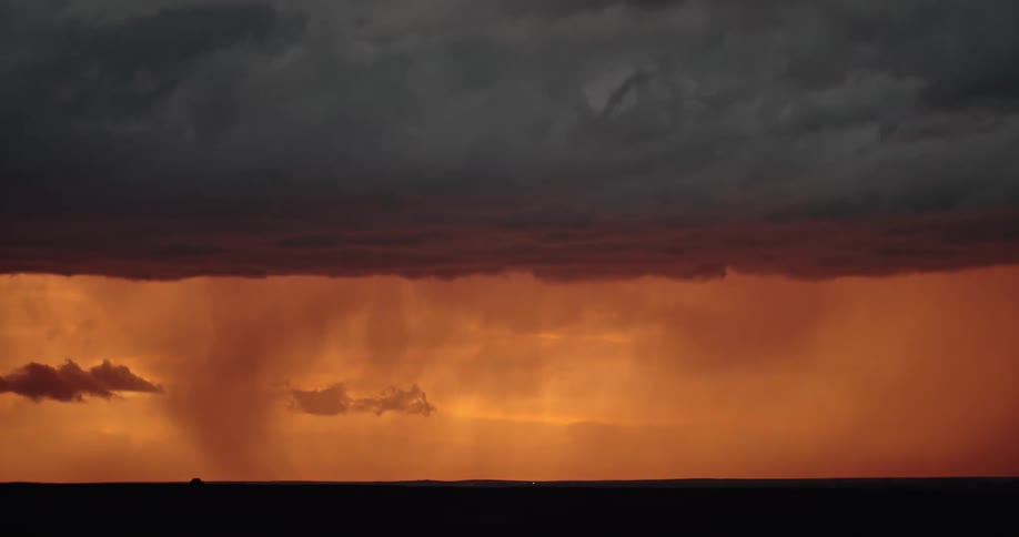 Lightning streaking arcs flashing over the silhouette of black clouds on a red sky