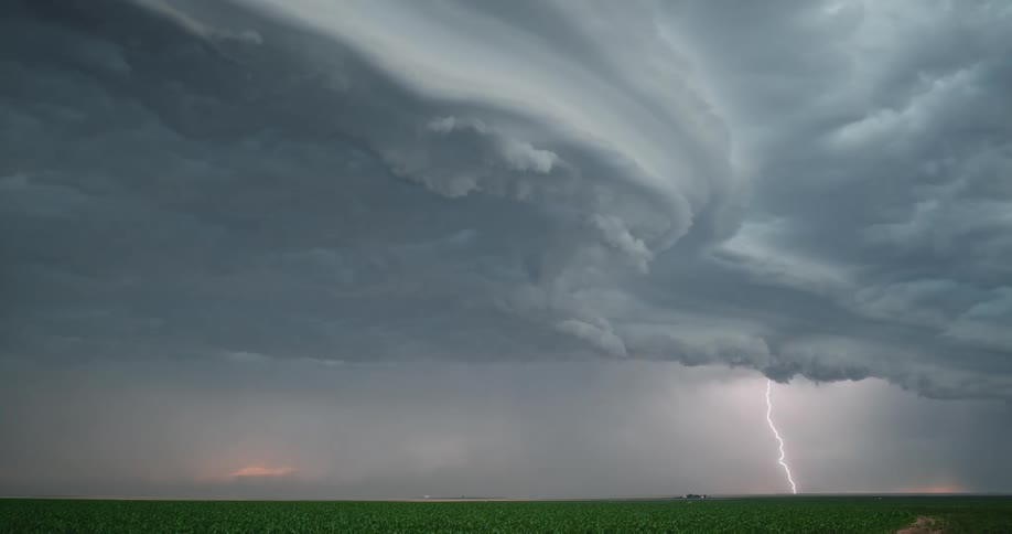 Bolts of lightning strike the ground beneath swirling and enormous storm clouds