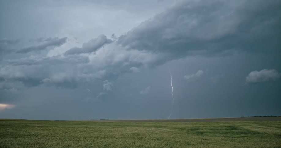 Lightning streaking arcs flashing accross storm clouds over a field