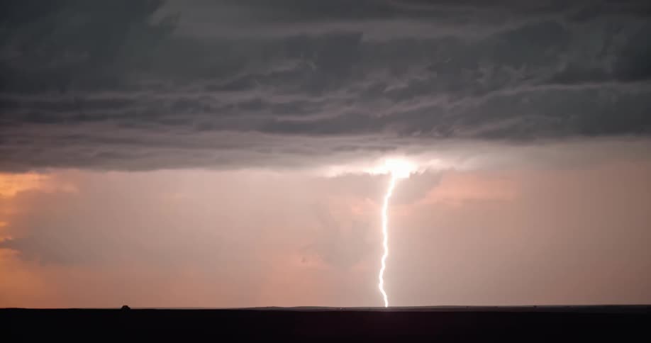 Lightning flashing in a cloudy orange sky during a rainstorm