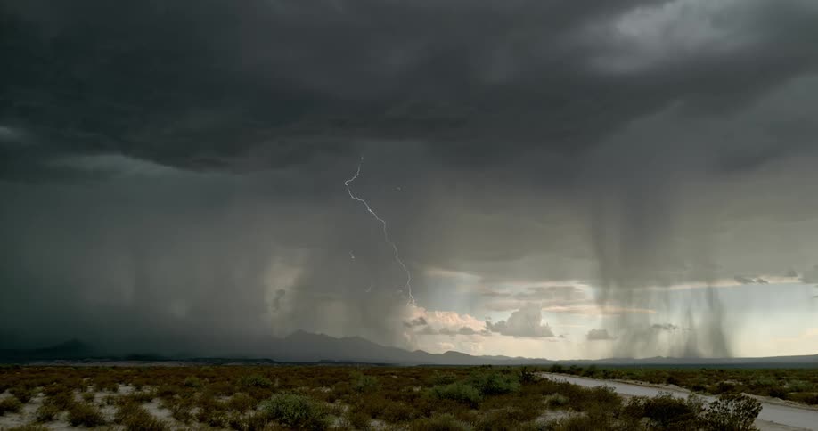 Dark clouds and lightning over a landscape of a wide open field