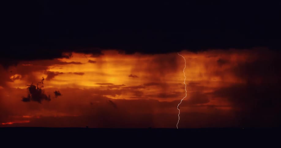 Powerful bolts of lighting shoot out of the clouds above a red sky and strike the ground below