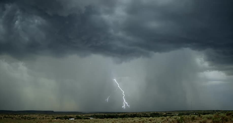 Lightning bolts flash and branch out from dark storm clouds as they hit the ground