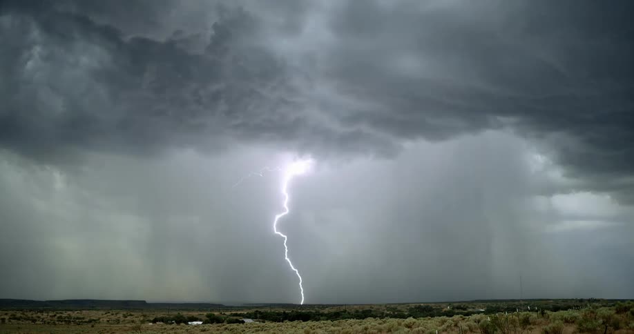 Lightning bolts flash and branch out from dark storm clouds as they hit the ground