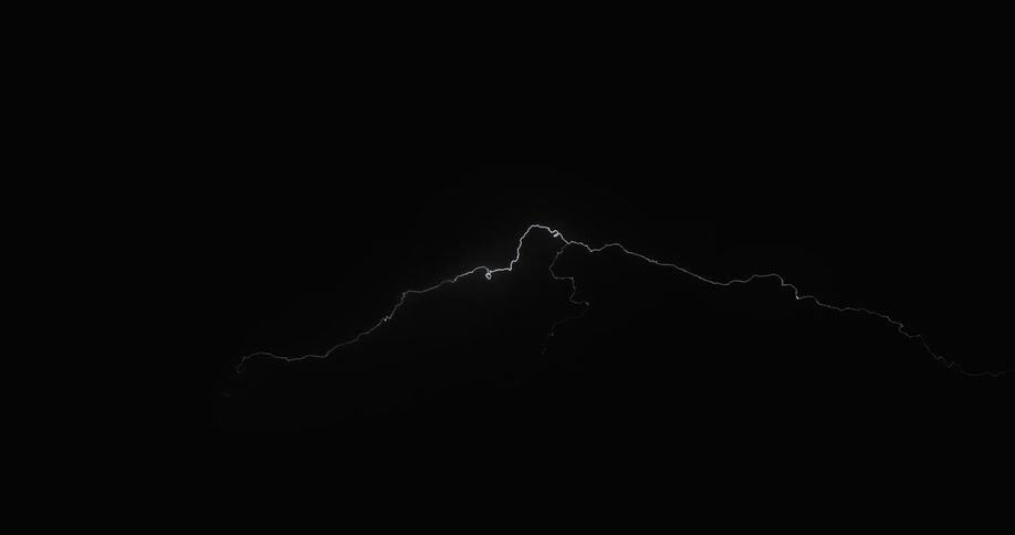 Lightning strikes and scatters across a dark sky in storm clouds at nighttime