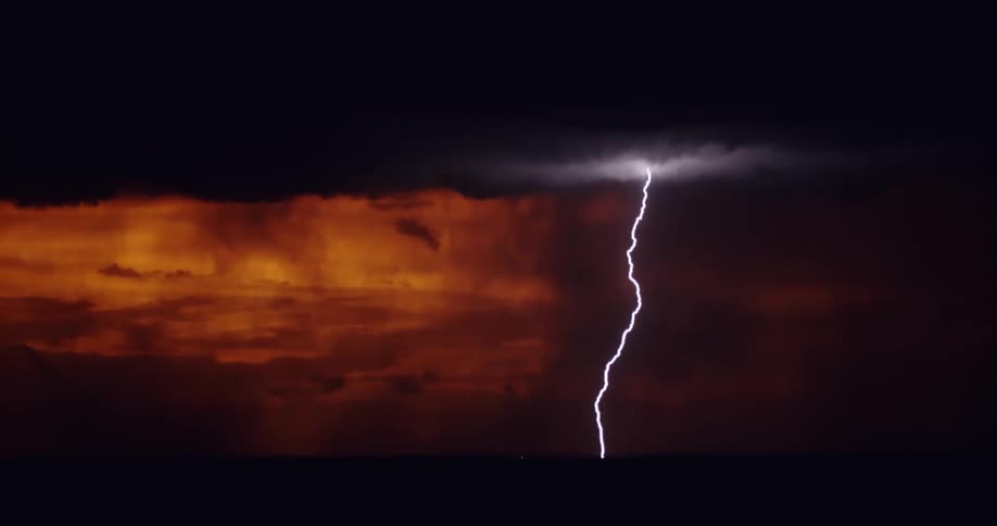 Enormously powerful bolts of lightning descend from the clouds in front of a red sky