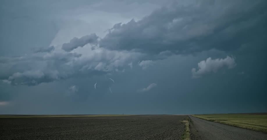 Lightning bolts flashing down from storm clouds near a road