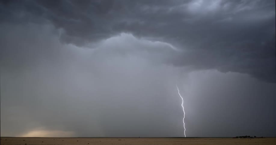 Lightning streaking arcs flashing across storm clouds hitting the ground over a field