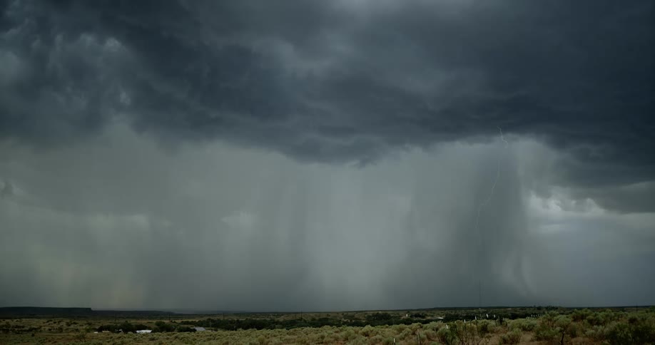 Lightning bolt from dark storm clouds branches out and hits the ground