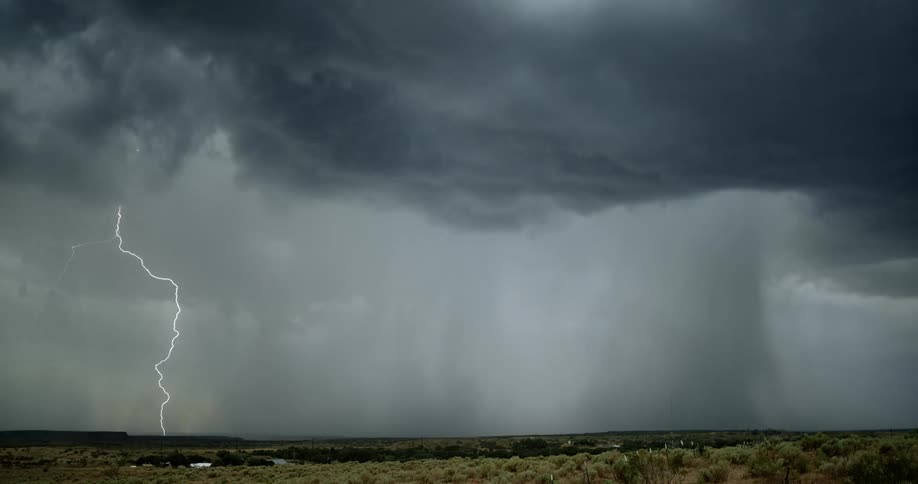 Lightning bolts flash from dark storm cloud and hit the ground