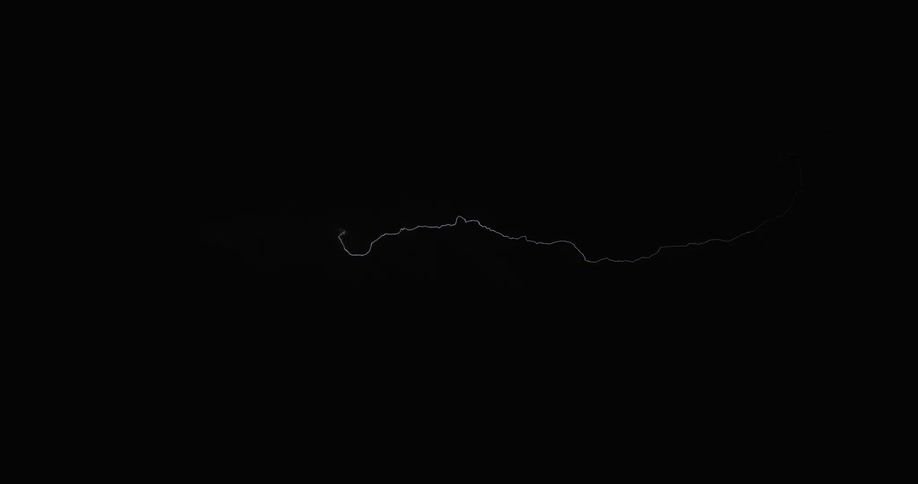 A flash of lightning strikes across a dark sky in a line in between clouds