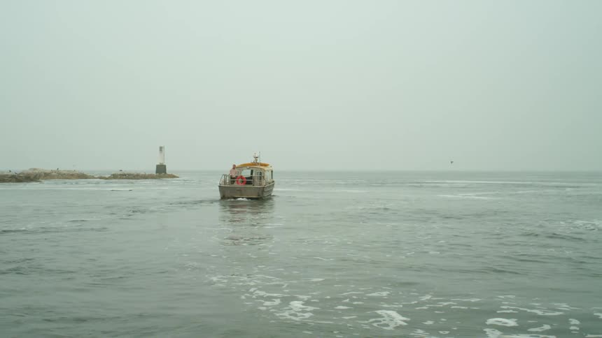 A boat on the ocean with birds flying in the sky and clouds in the background