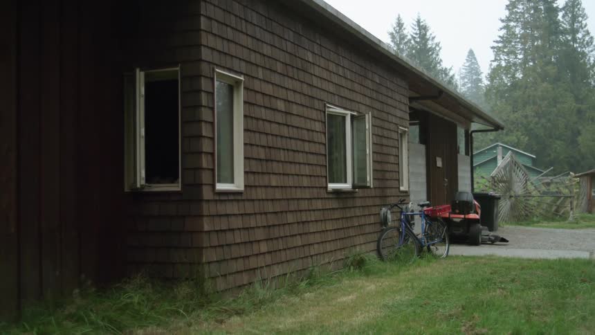 A bicycle next to a brown house on a summer day