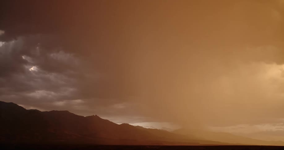 Lightning streaking arcs flashing across yellow storm clouds hitting the ground over the mountains