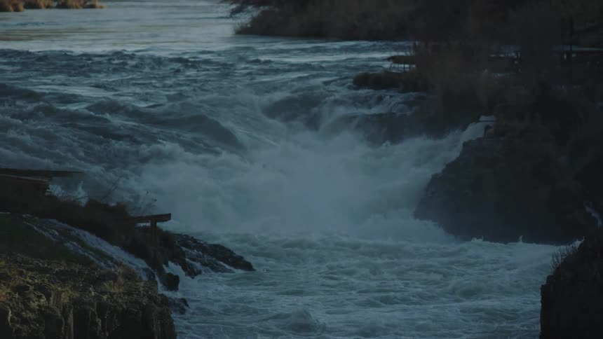 Whitewater cascades down a huge river flume as the camera dynamically moves through the sunset moment
