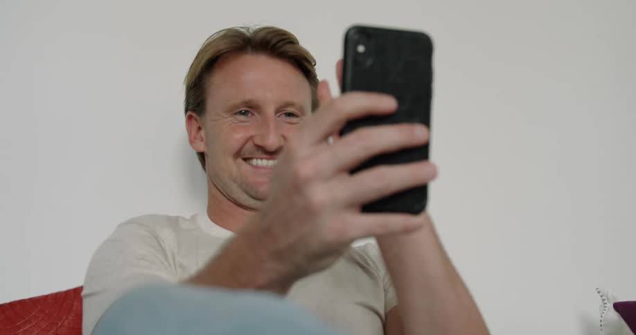 A man sits and has a video call on a cell phone