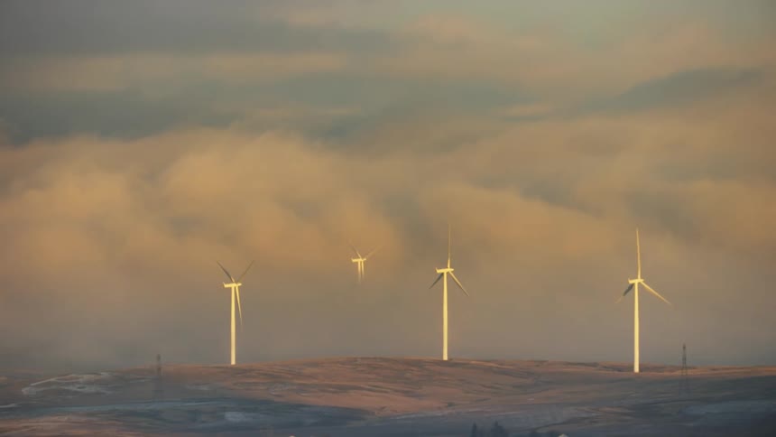 Power generating wind mills generate clean and renewable power from sunrise clouds on a cold winter morning on rural farm land