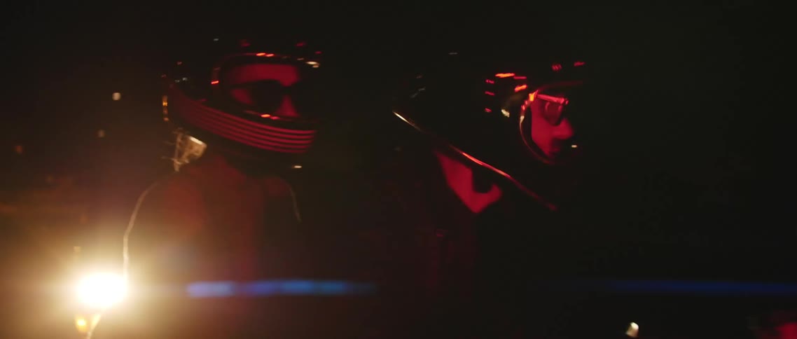 A man and woman are riding motorcycles at night