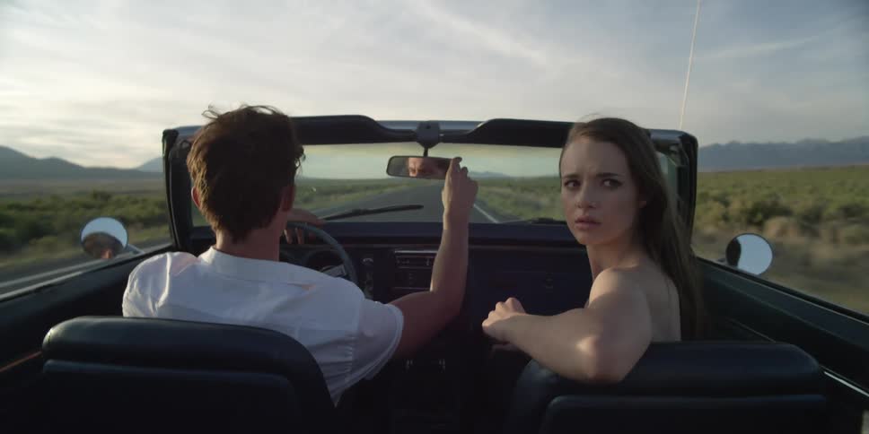A man and woman are driving a car in a rural area